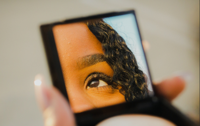 Reflet partiel d'un visage de femme dans un miroir portatif.