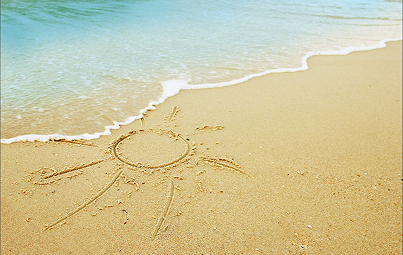 Dessin de soleil gravé dans le sable d'une plage, disparaissant sous l'écume.